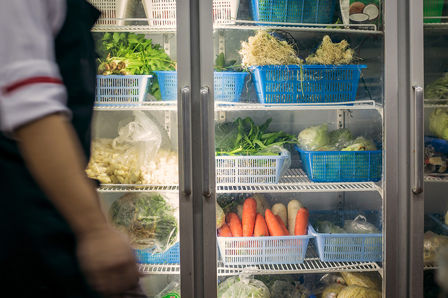 Commercial refrigerator with various vegetables shown inside.